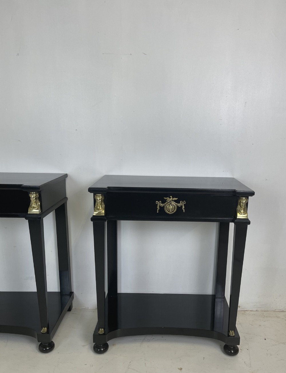 A pair of ebonised black side tables featuring single drawers, lower shelves, and gilt brass mounts on square legs. View II