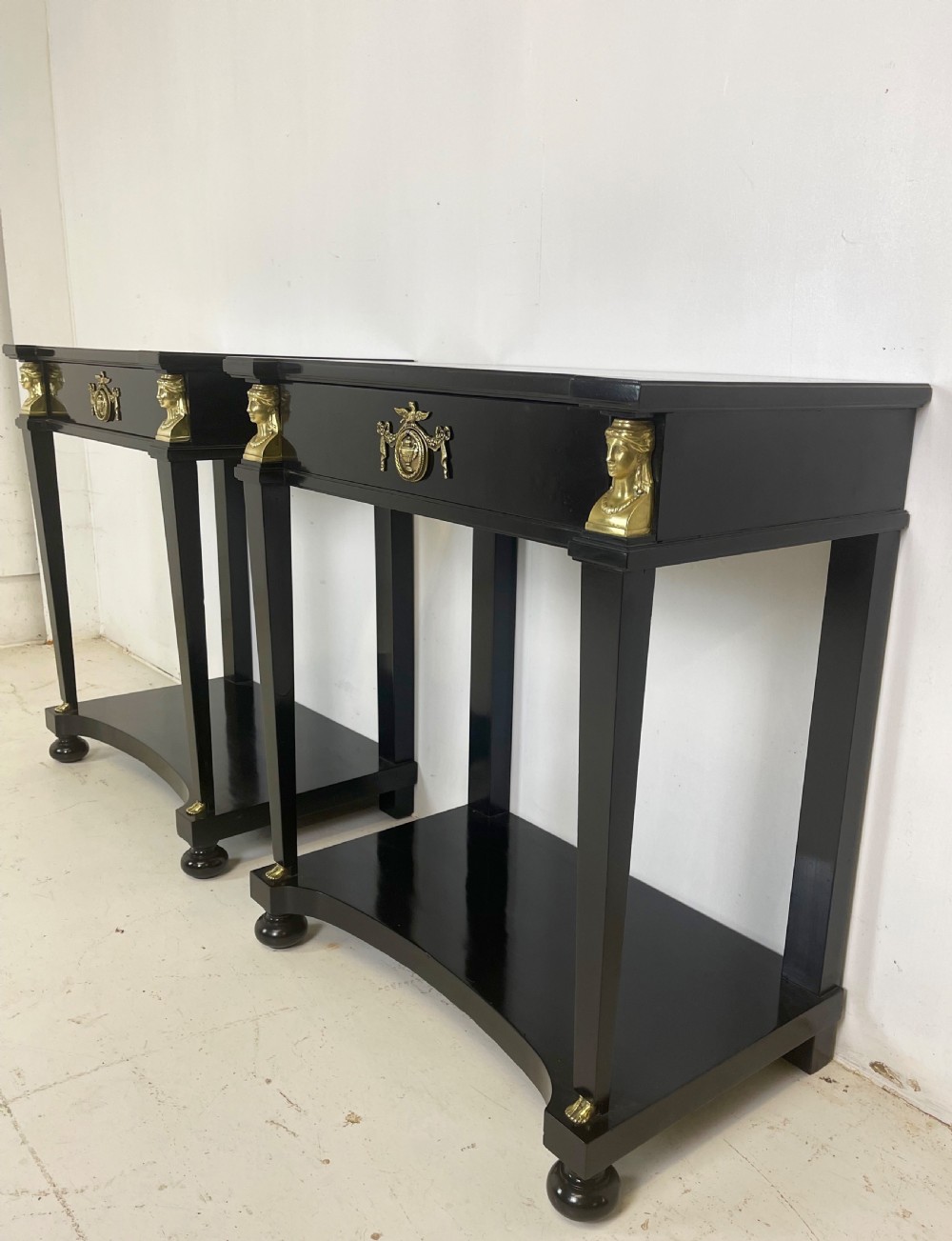 A pair of ebonised black side tables featuring single drawers, lower shelves, and gilt brass mounts on square legs. View IV
