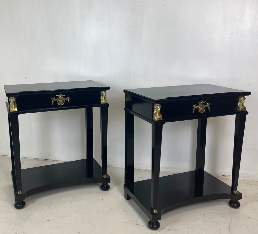 A pair of ebonised black side tables featuring single drawers, lower shelves, and gilt brass mounts on square legs. View VII