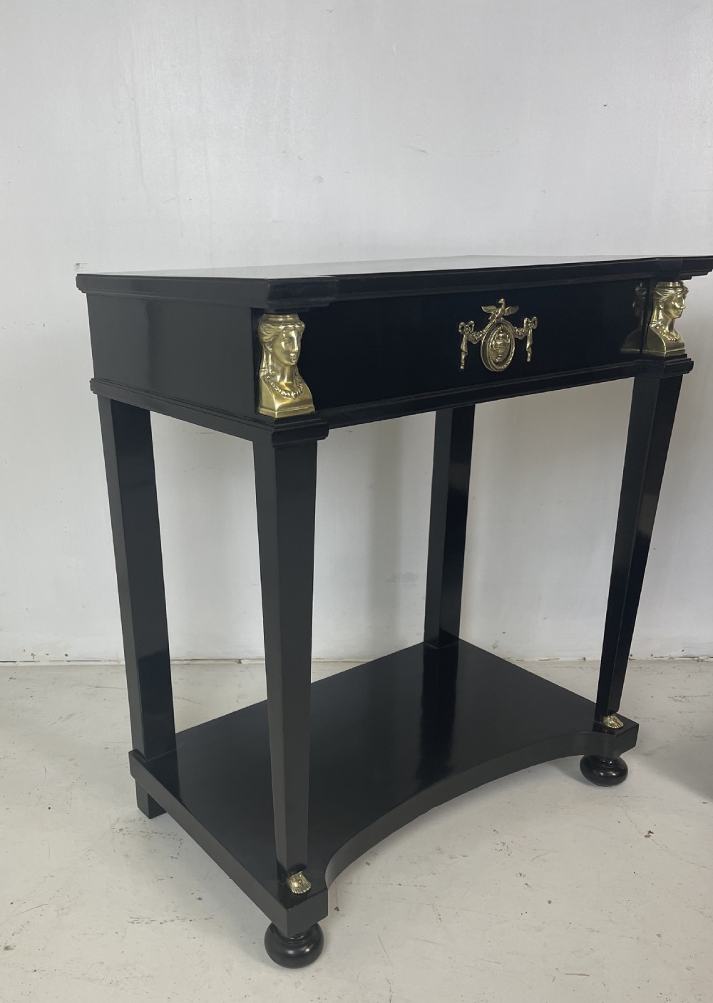 A pair of ebonised black side tables featuring single drawers, lower shelves, and gilt brass mounts on square legs. View VIII