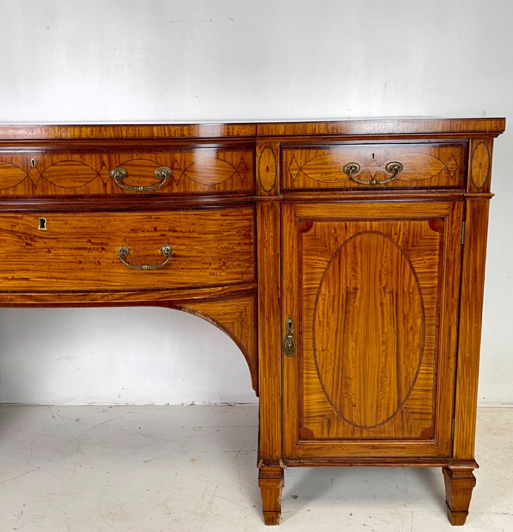 An Edwardian satinwood sideboard featuring oval marquetry inlays, drawers, two side cupboard doors, and tapered legs. View II