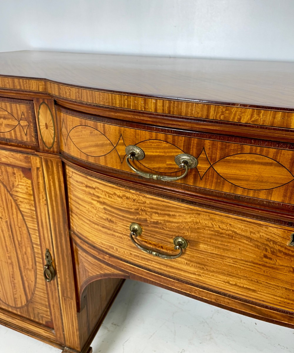 An Edwardian satinwood sideboard featuring oval marquetry inlays, drawers, two side cupboard doors, and tapered legs. View V