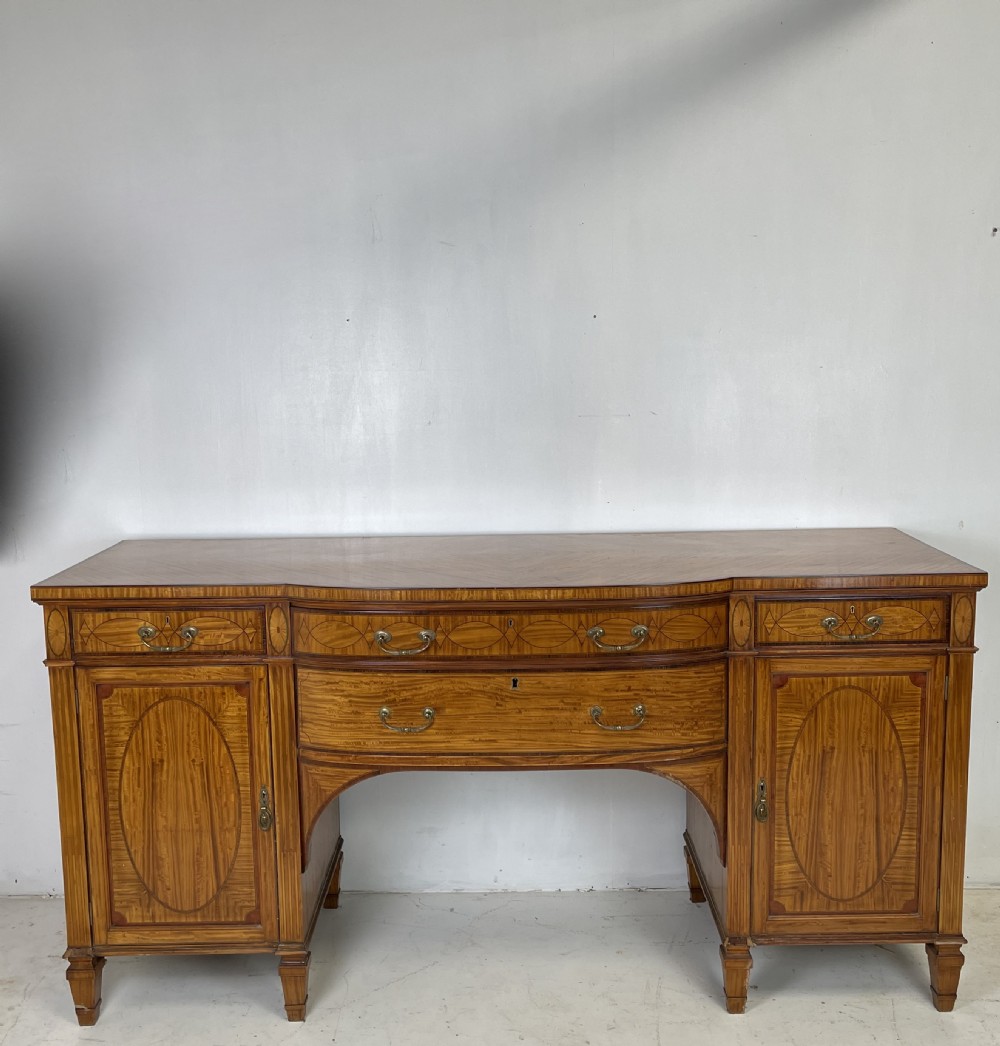 An Edwardian satinwood sideboard featuring oval marquetry inlays, drawers, two side cupboard doors, and tapered legs. View XI