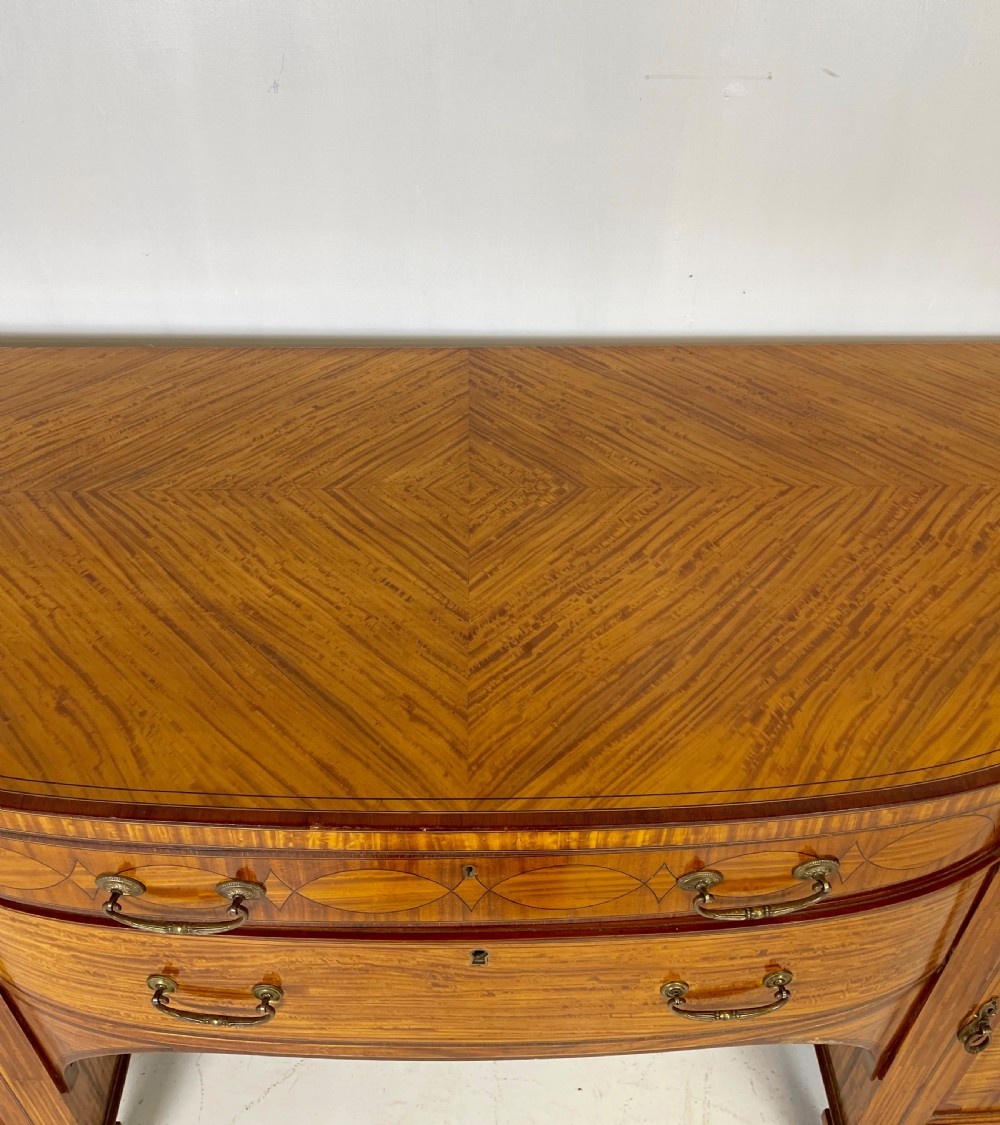 An Edwardian satinwood sideboard featuring oval marquetry inlays, drawers, two side cupboard doors, and tapered legs. View XII