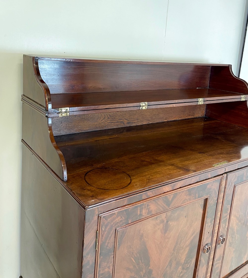 A pair of mahogany serving cupboards with flame veneer doors and folding upper gallery shelves. View V