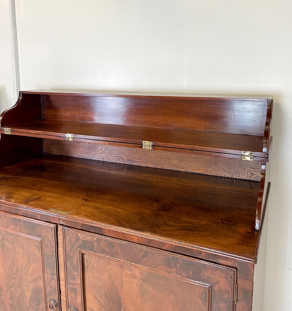 A pair of mahogany serving cupboards with flame veneer doors and folding upper gallery shelves. View VII