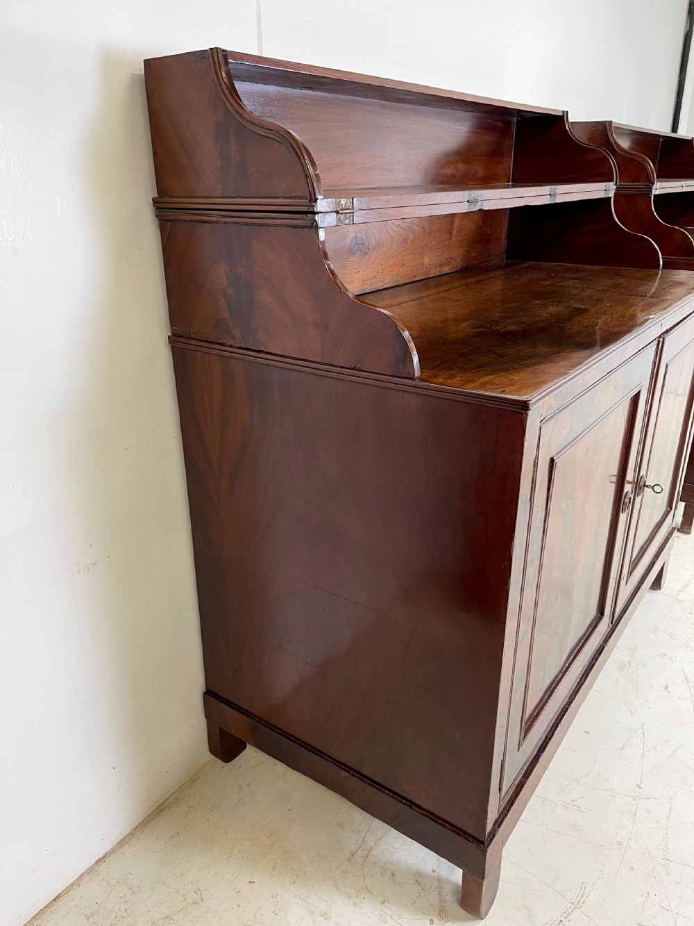 A pair of mahogany serving cupboards with flame veneer doors and folding upper gallery shelves. View XI