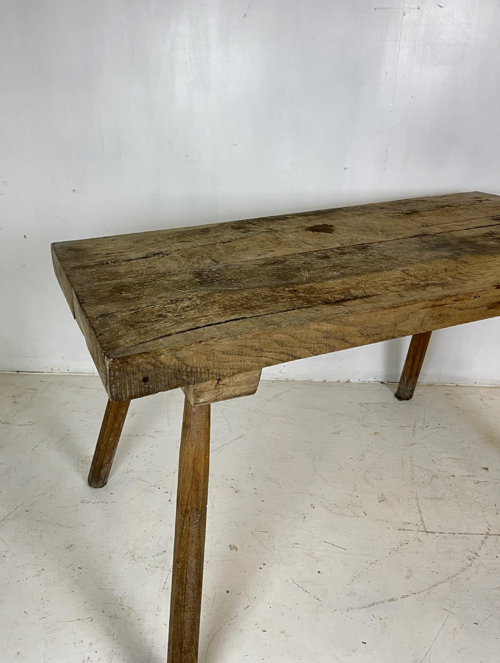 An antique rustic wooden work table featuring a thick timber top supported by four splayed cylindrical legs with visible wear and grain. View VIII