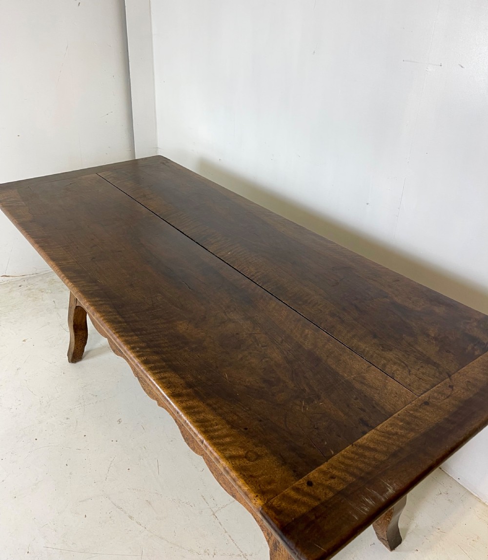 An antique French walnut dough bin featuring a flat overhanging top, sloped timber sides, and a scalloped apron resting on short legs. View IV