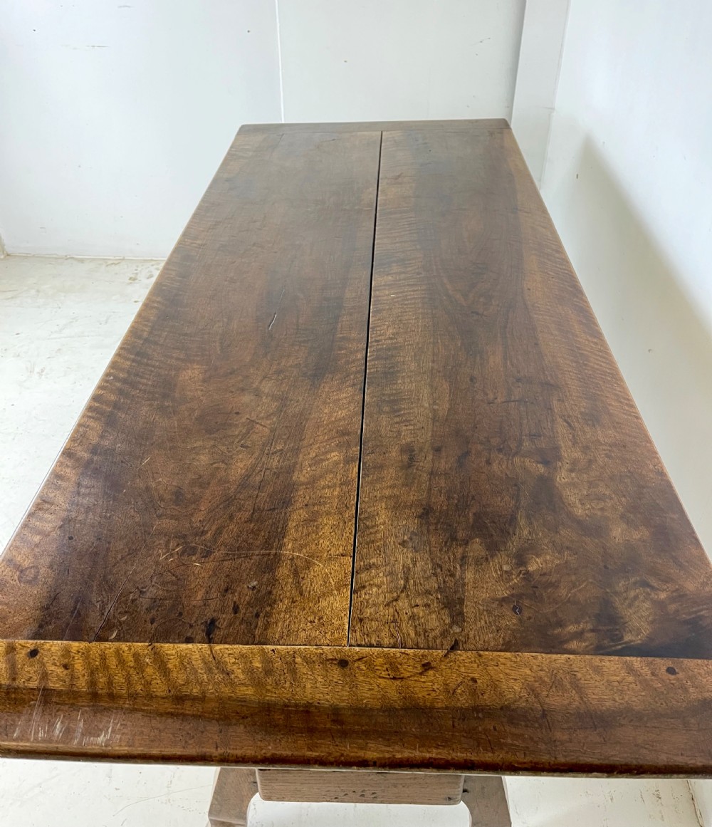 An antique French walnut dough bin featuring a flat overhanging top, sloped timber sides, and a scalloped apron resting on short legs. View V