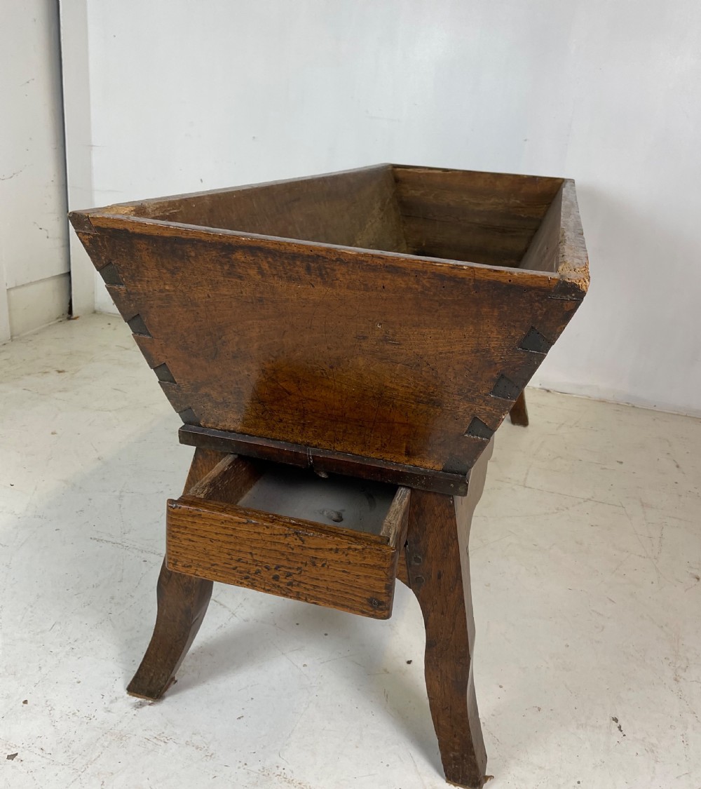 An antique French walnut dough bin featuring a flat overhanging top, sloped timber sides, and a scalloped apron resting on short legs. View VIII