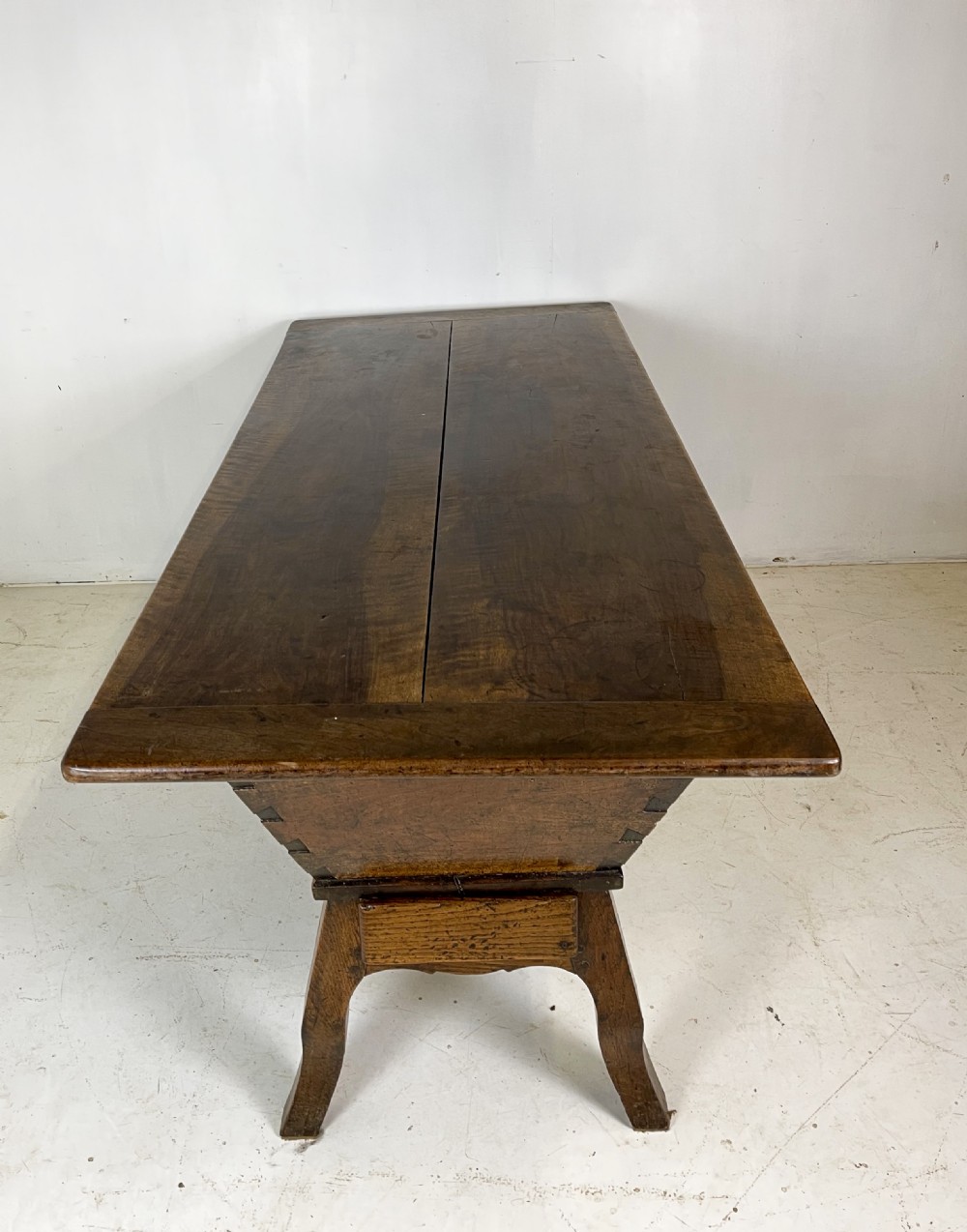 An antique French walnut dough bin featuring a flat overhanging top, sloped timber sides, and a scalloped apron resting on short legs. View X