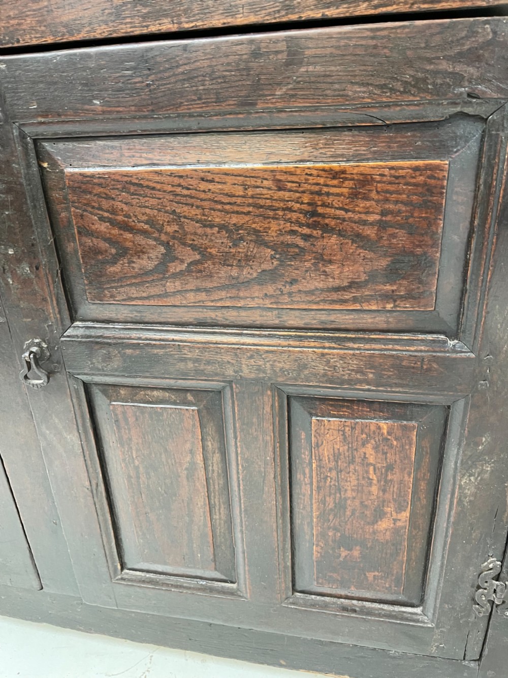 A dark oak joined court cupboard featuring a recessed upper section with geometric panelled doors and turned drop finials above a two-door base. View VI
