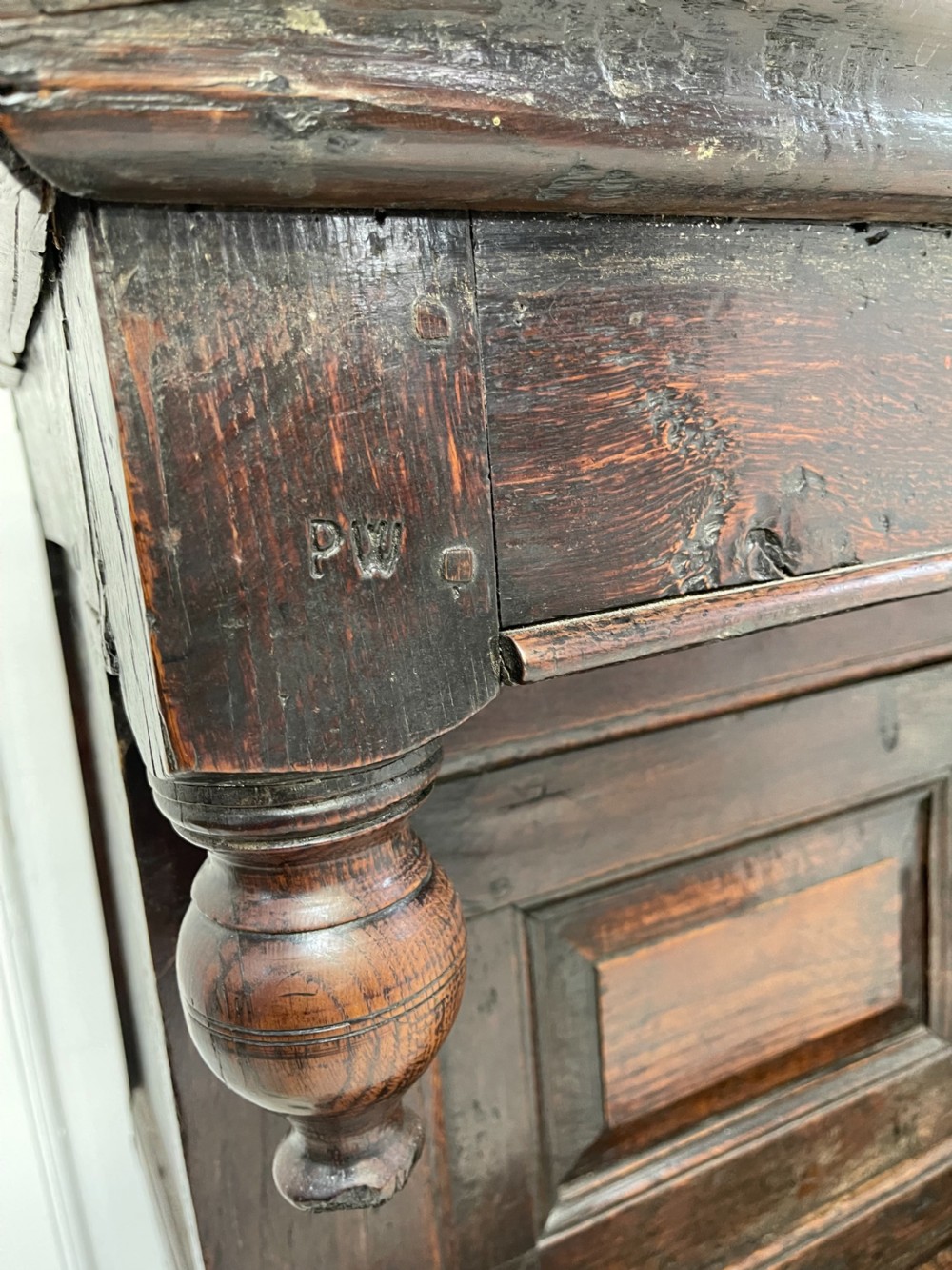 A dark oak joined court cupboard featuring a recessed upper section with geometric panelled doors and turned drop finials above a two-door base. View VIII