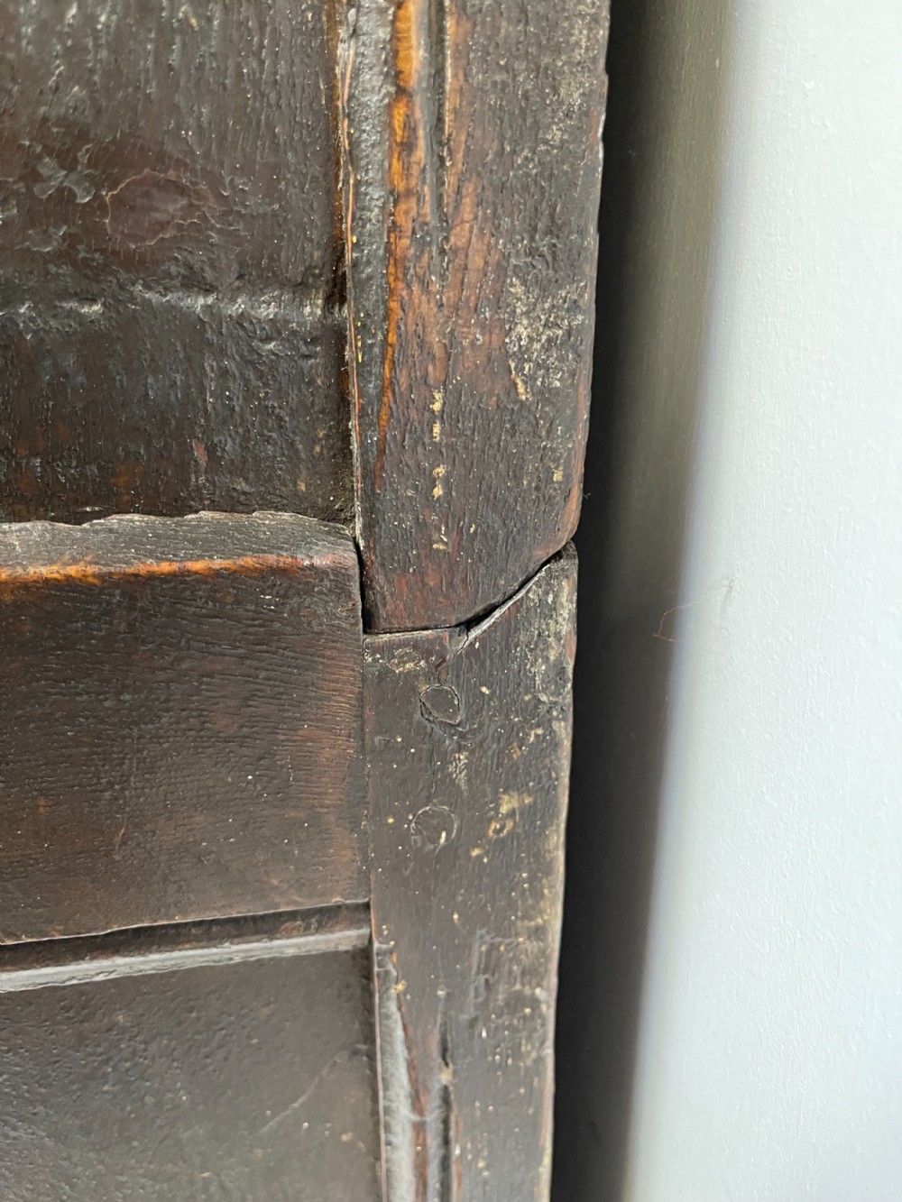 A dark carved oak court cupboard featuring upper and lower double doors with geometric diamond panels, guilloche frieze carving, and turned side supports. View VII