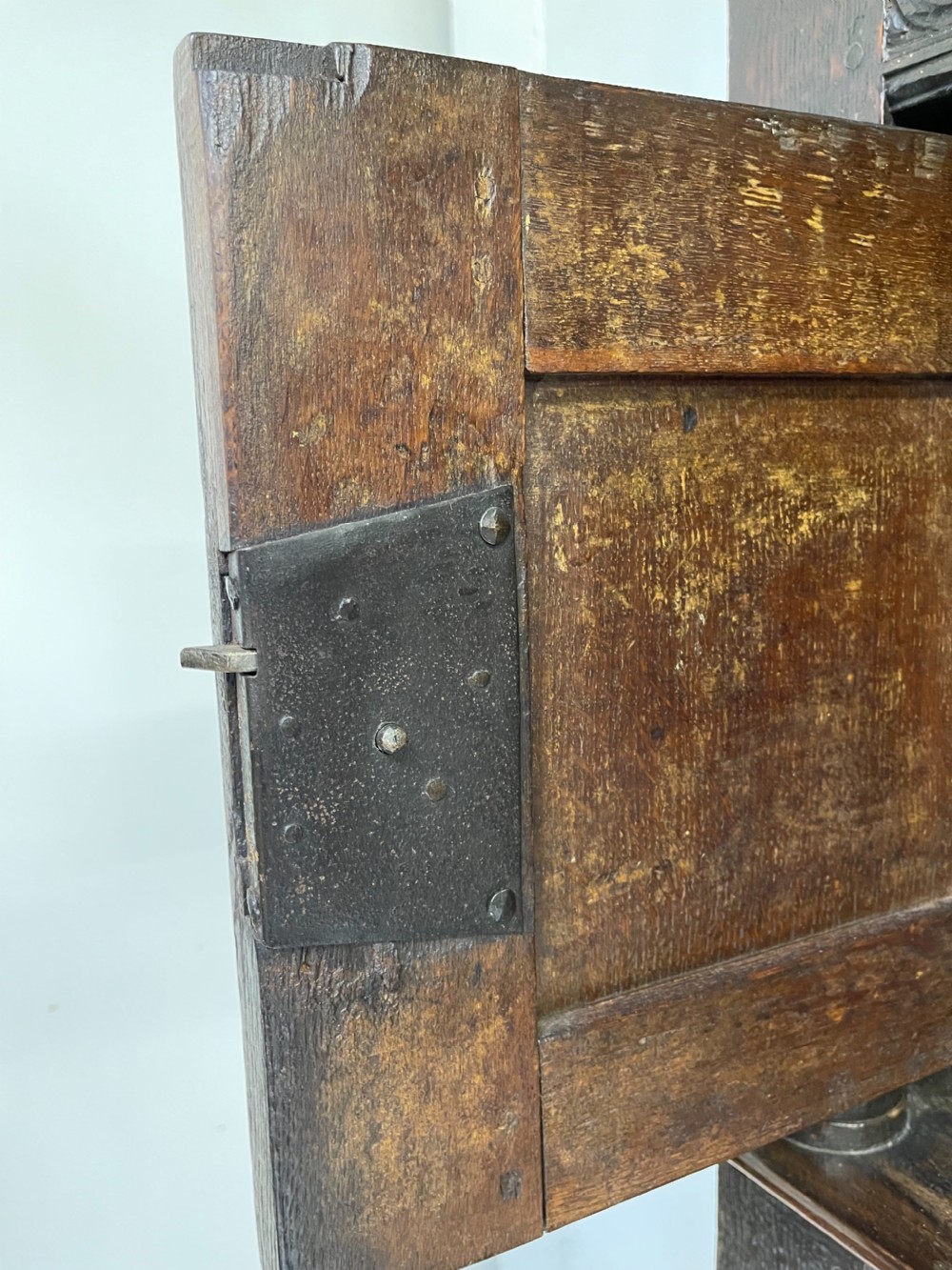 A dark carved oak court cupboard featuring upper and lower double doors with geometric diamond panels, guilloche frieze carving, and turned side supports. View XI