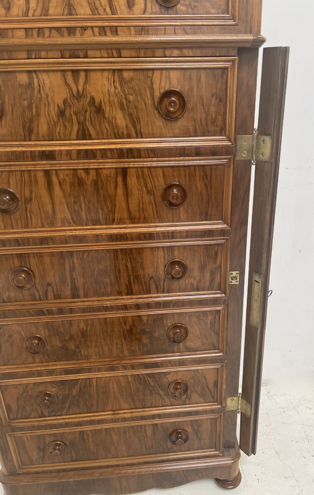 A tall Victorian walnut Wellington chest with seven graduated drawers, turned wooden knobs, and a hinged side-locking bar. View VI