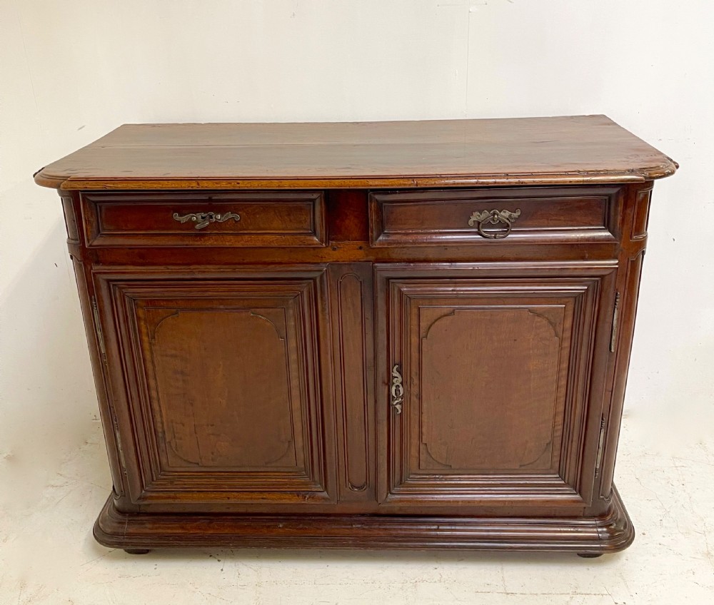 An antique French walnut buffet featuring two top drawers above two moulded panel cupboard doors with iron hardware and a solid plinth base.