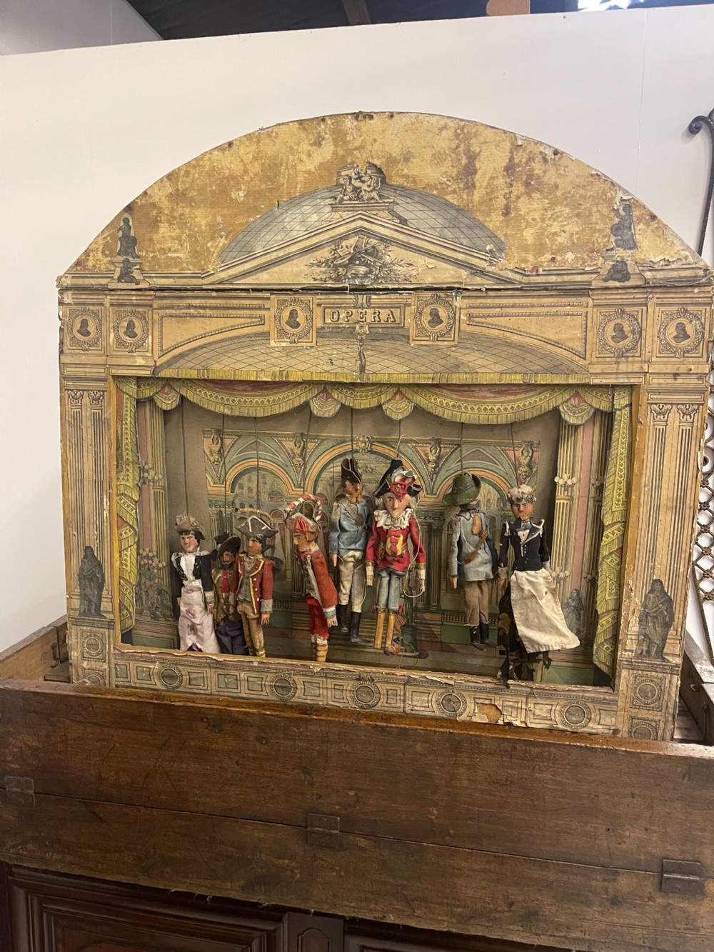 An antique wooden and paper toy puppet theatre labelled Opera, featuring miniature costumed marionettes on a painted classical stage. View II