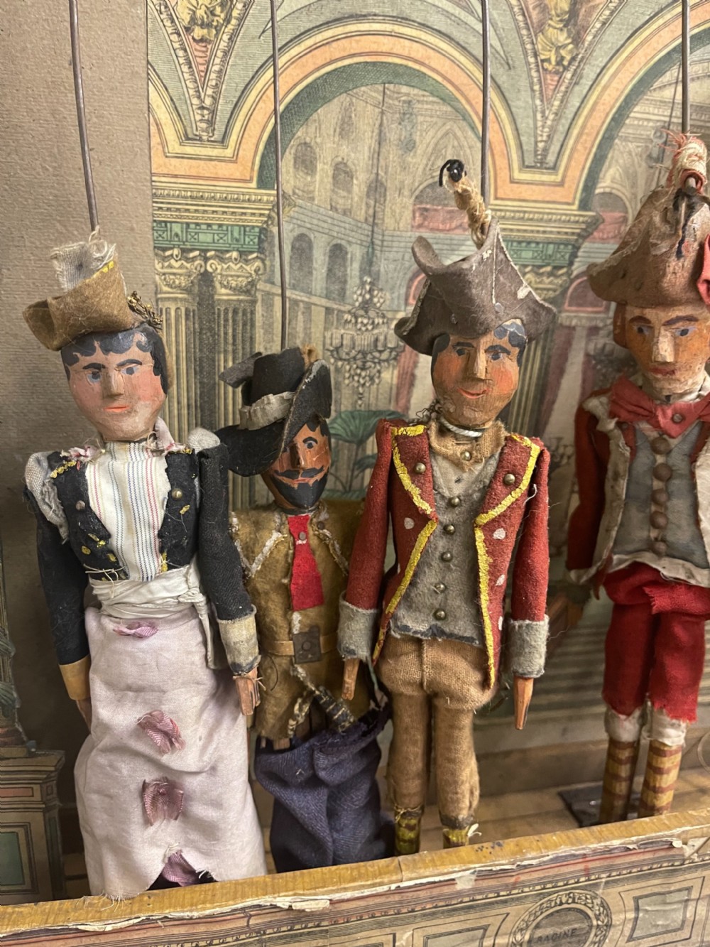 An antique wooden and paper toy puppet theatre labelled Opera, featuring miniature costumed marionettes on a painted classical stage. View VII