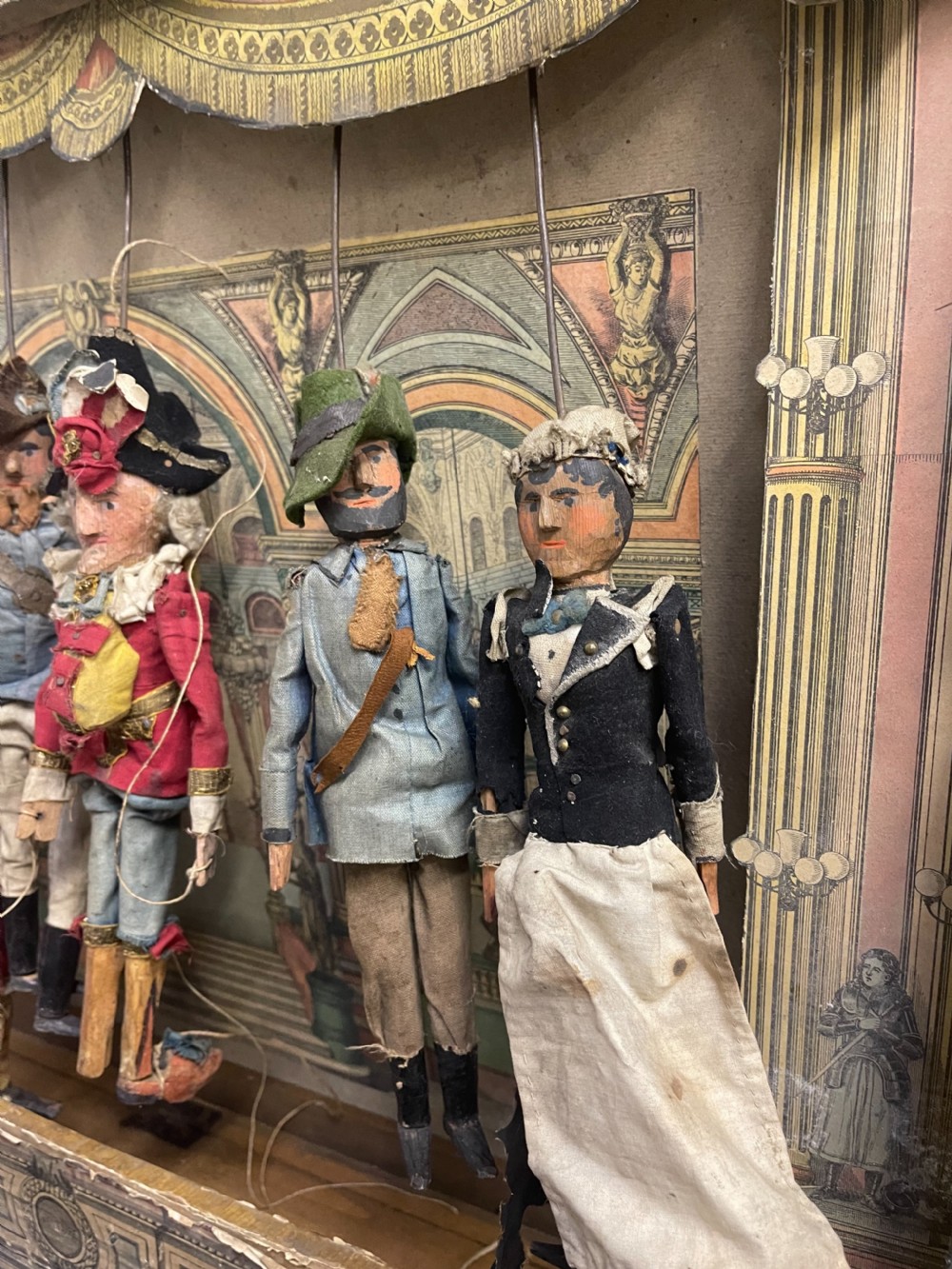 An antique wooden and paper toy puppet theatre labelled Opera, featuring miniature costumed marionettes on a painted classical stage. View IX