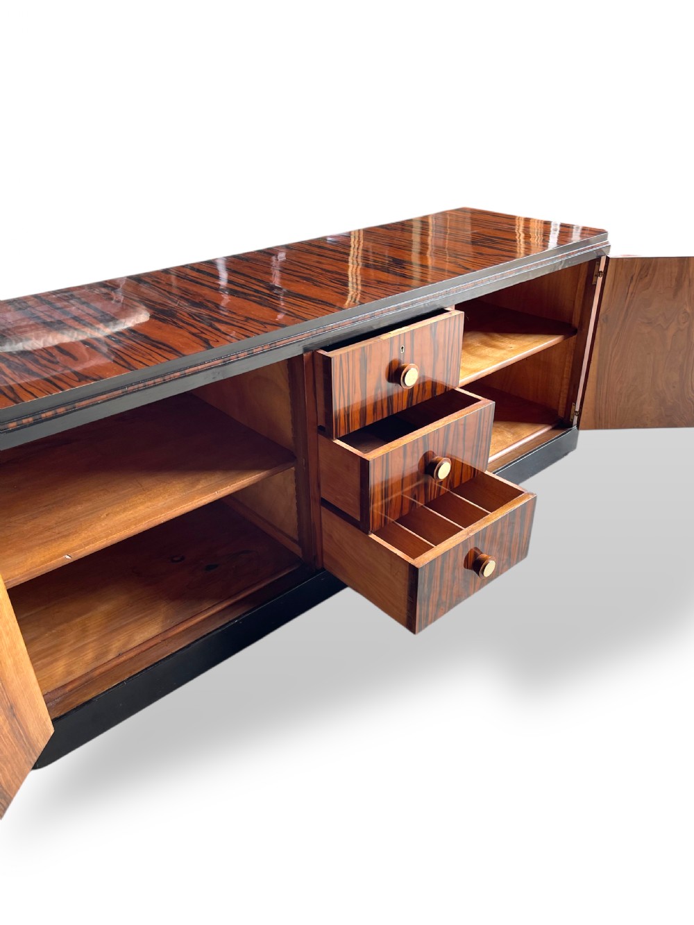 A low-profile French Art Deco sideboard in high-gloss Macassar ebony veneer with central drawers and geometric side door details. View XV