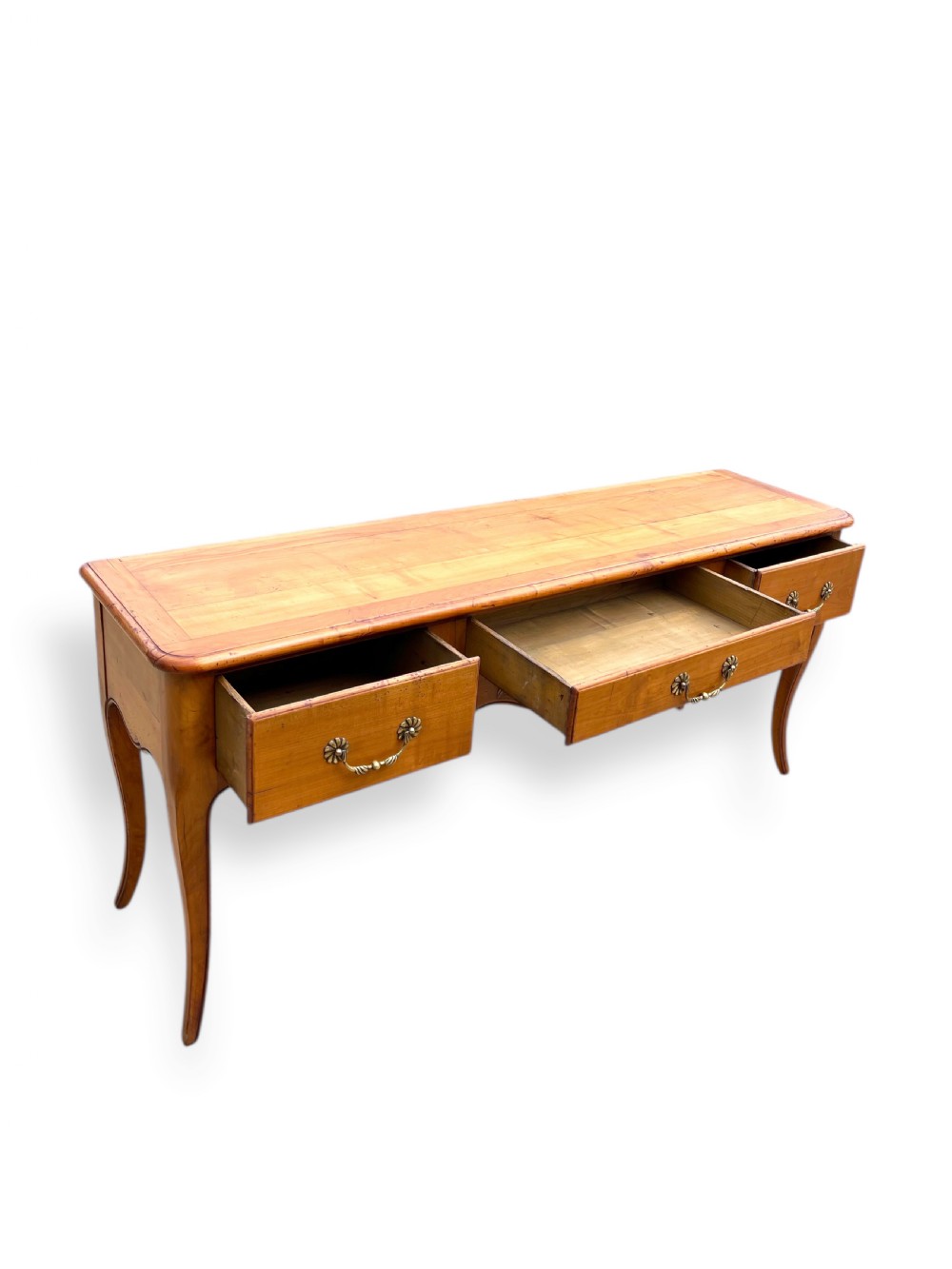 A French provincial cherrywood serving table featuring three drawers with brass drop handles, a hand-carved central shell motif on the apron, and slender cabriole legs. View IV