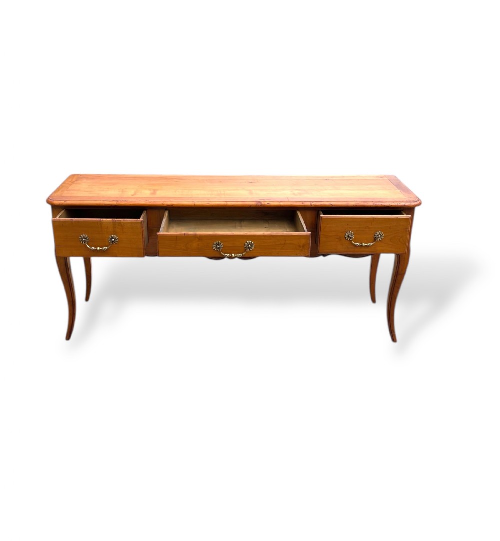 A French provincial cherrywood serving table featuring three drawers with brass drop handles, a hand-carved central shell motif on the apron, and slender cabriole legs. View V