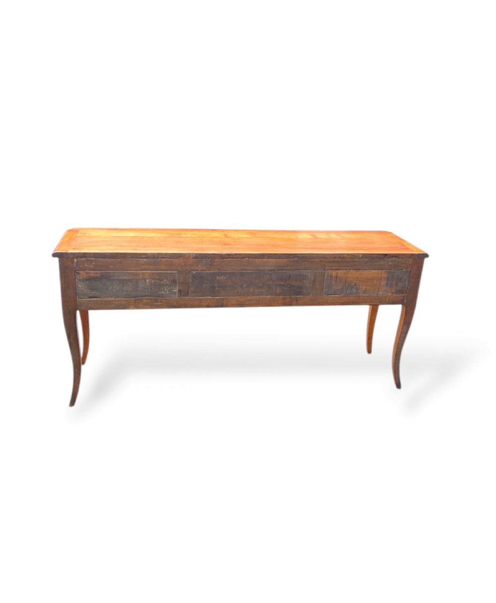 A French provincial cherrywood serving table featuring three drawers with brass drop handles, a hand-carved central shell motif on the apron, and slender cabriole legs. View X