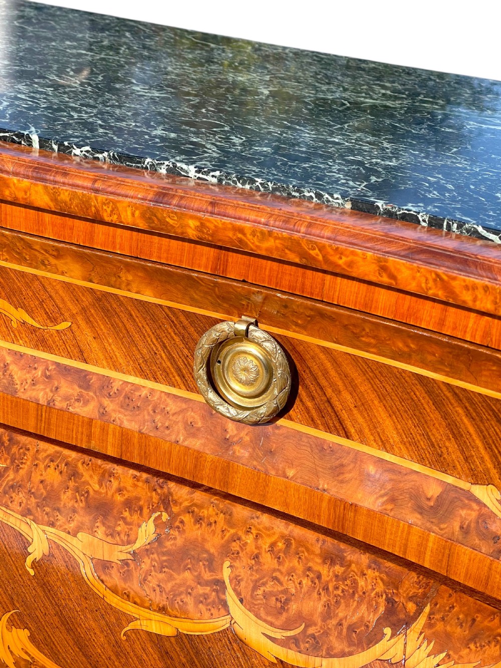A pair of Italian bombe commodes featuring intricate floral marquetry timber inlays, dark green marble tops, and brass handles. View X