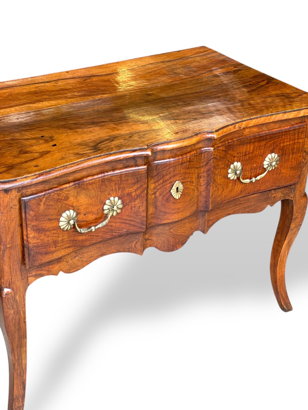 An 18th-century French walnut side table featuring a contoured serpentine front, single drawer with decorative brass handles, a shaped apron, and curved cabriole legs. View IX