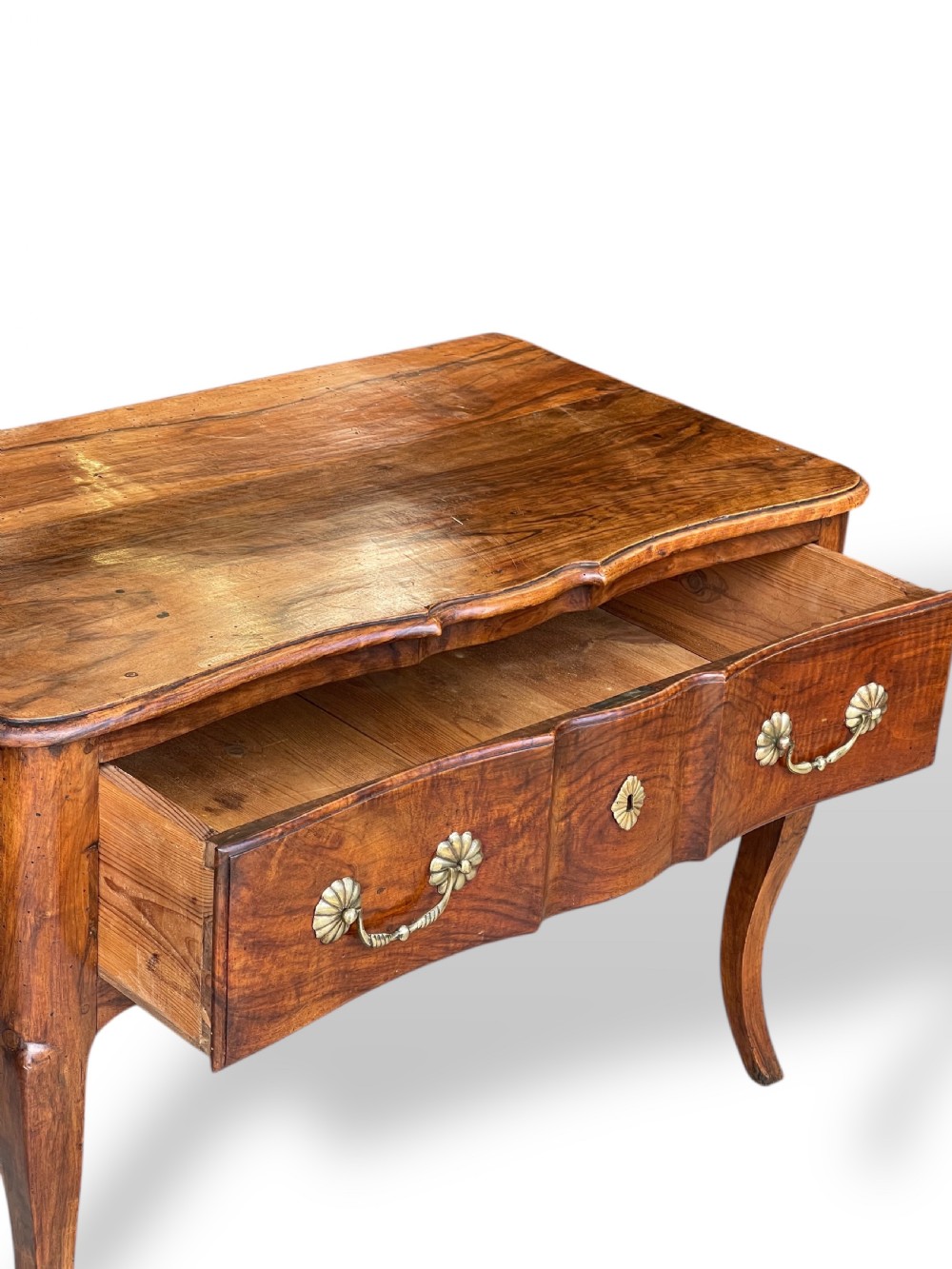 An 18th-century French walnut side table featuring a contoured serpentine front, single drawer with decorative brass handles, a shaped apron, and curved cabriole legs. View XVII