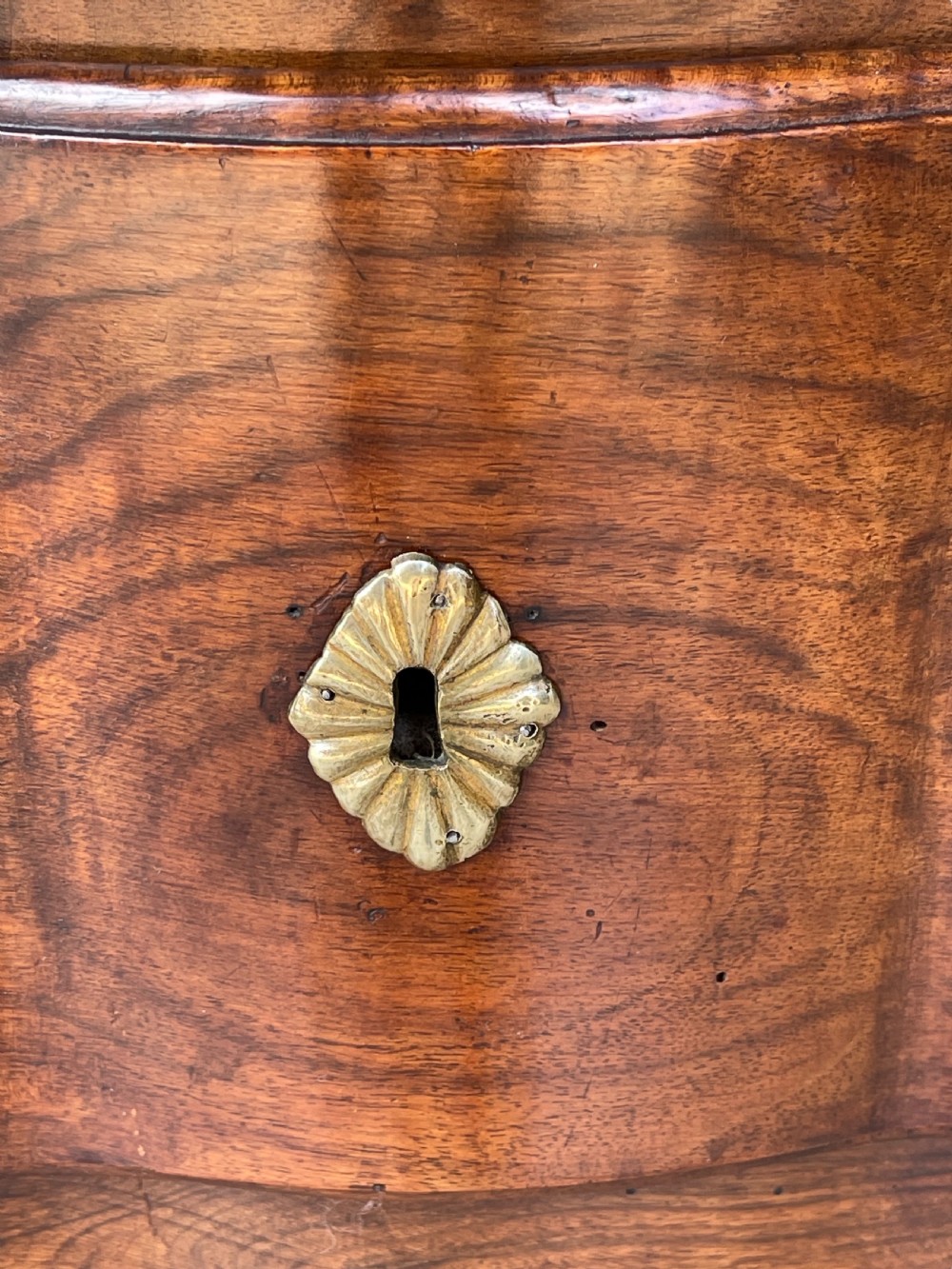 An 18th-century French walnut side table featuring a contoured serpentine front, single drawer with decorative brass handles, a shaped apron, and curved cabriole legs. View XVIII