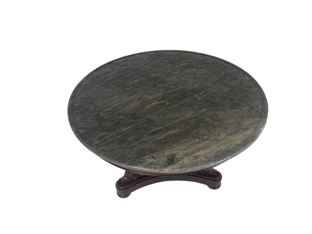 An early nineteenth-century French Empire gueridon table with a circular grey veined marble top resting on a mahogany base with carved ram heads.
