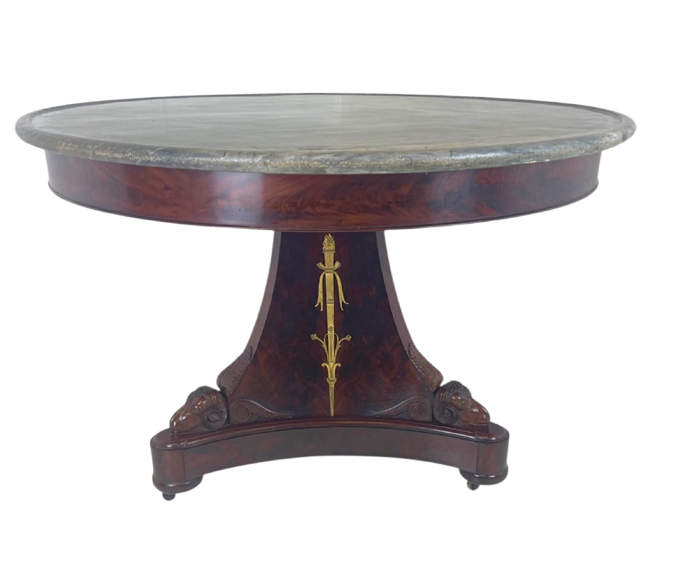 An early nineteenth-century French Empire gueridon table with a circular grey veined marble top resting on a mahogany base with carved ram heads. View II