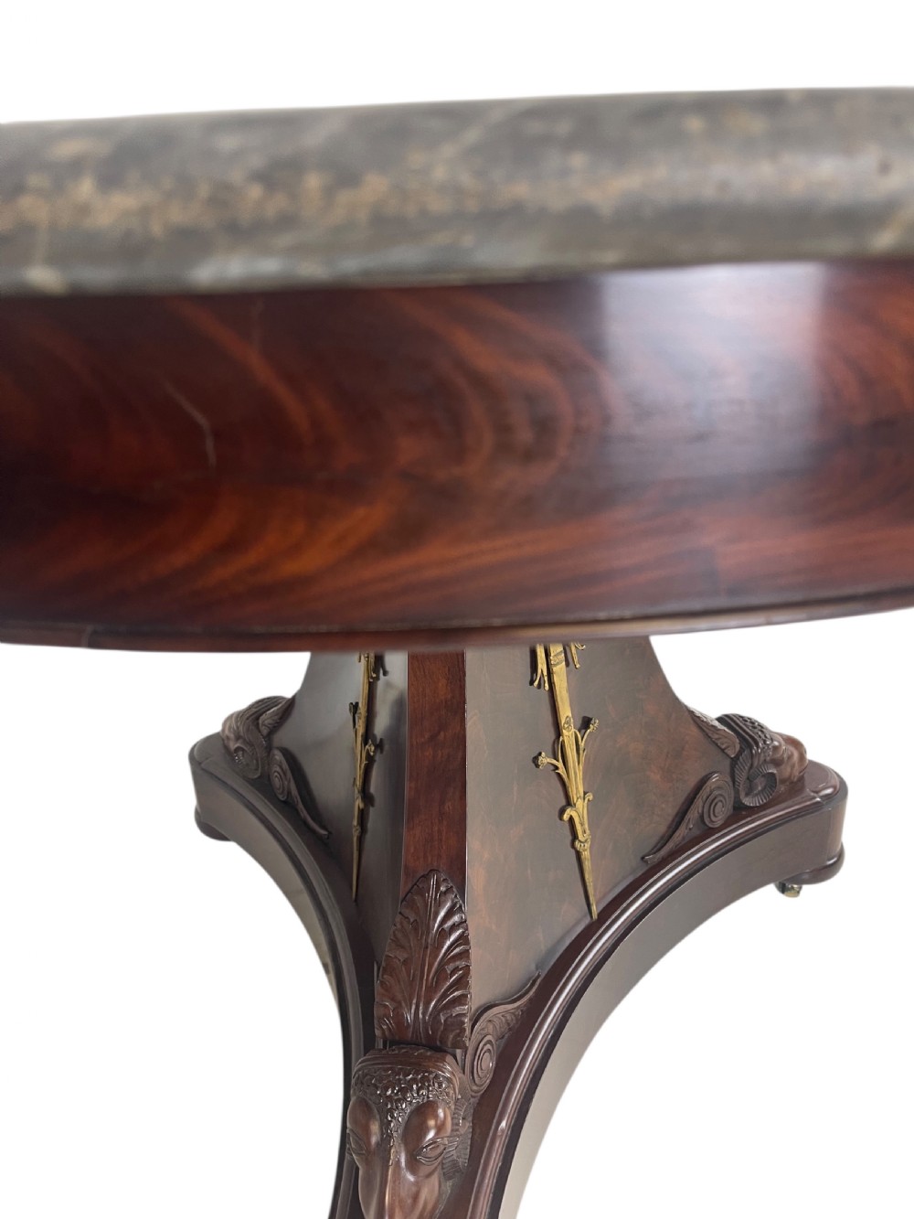 An early nineteenth-century French Empire gueridon table with a circular grey veined marble top resting on a mahogany base with carved ram heads. View VIII