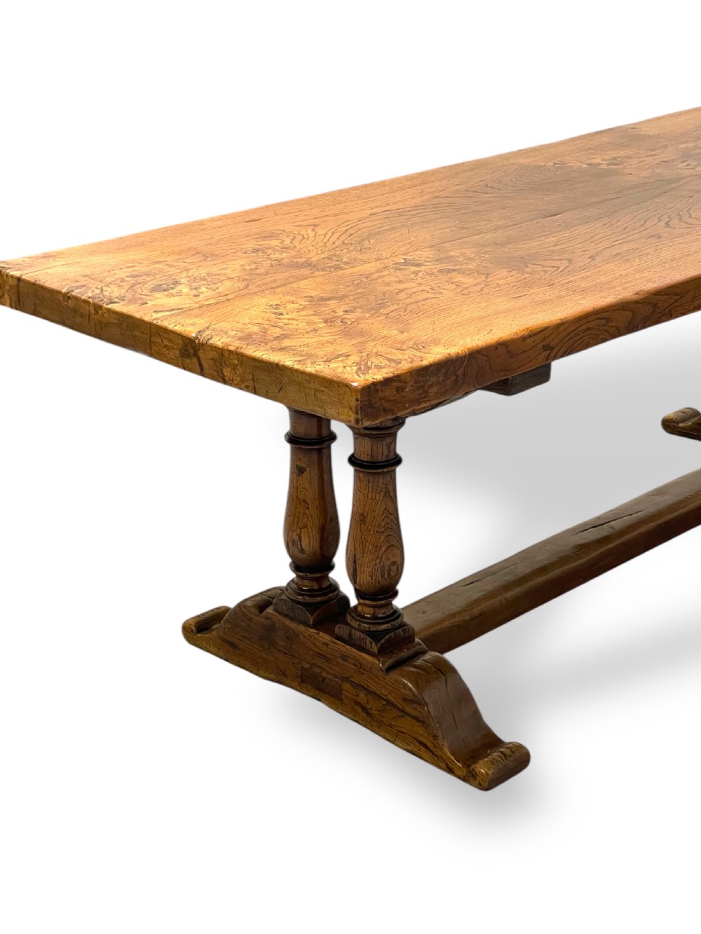 A solid warm brown oak refectory dining table featuring a thick rectangular top supported by double turned columns and a central stretcher. View II