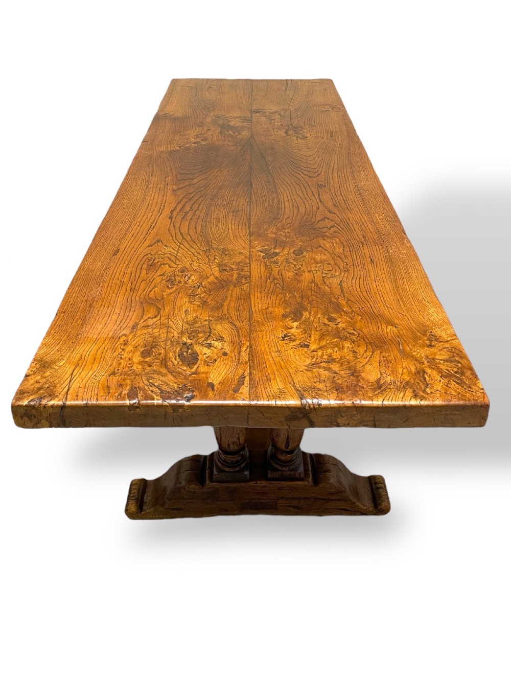 A solid warm brown oak refectory dining table featuring a thick rectangular top supported by double turned columns and a central stretcher. View III