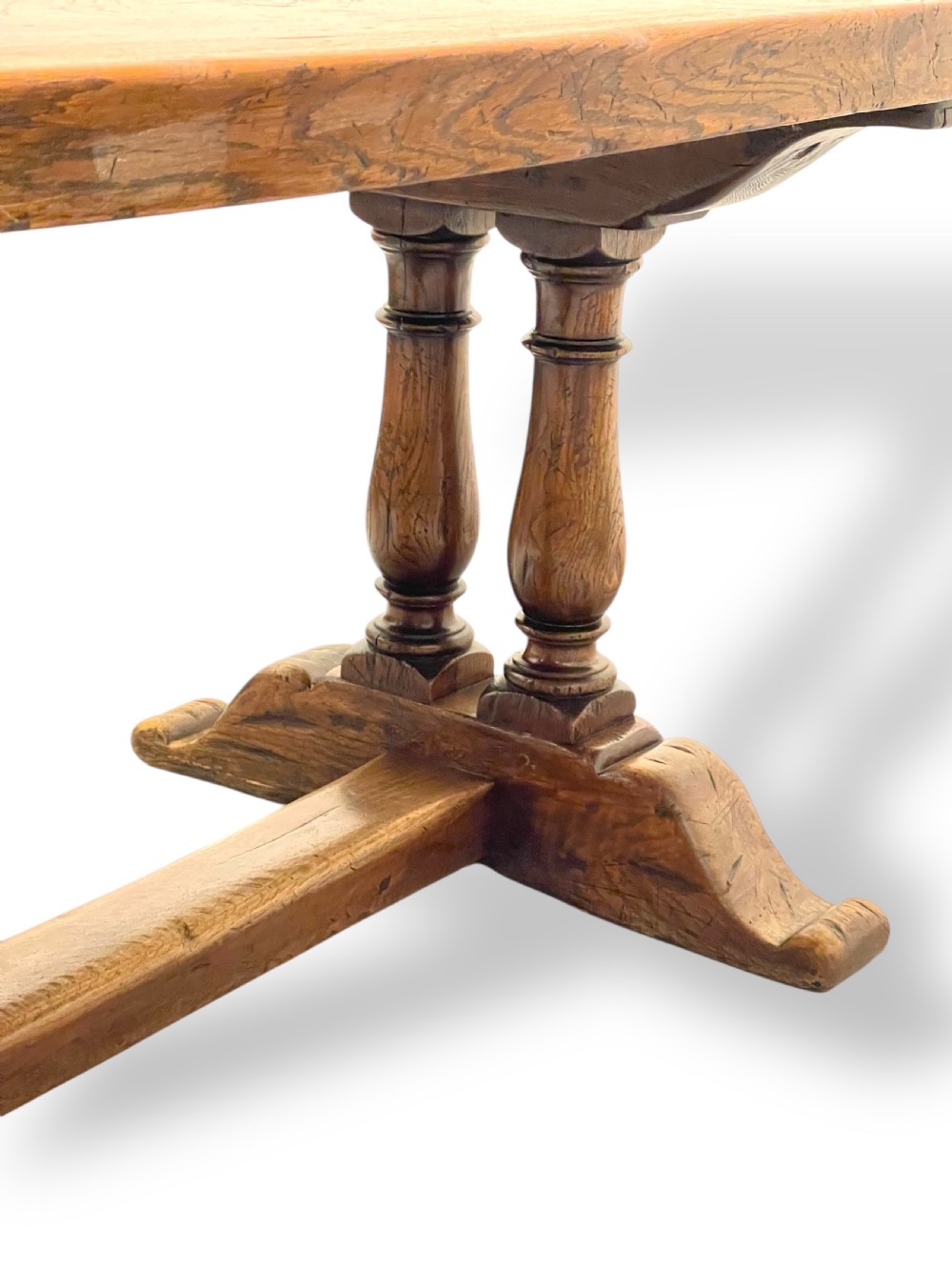 A solid warm brown oak refectory dining table featuring a thick rectangular top supported by double turned columns and a central stretcher. View VIII