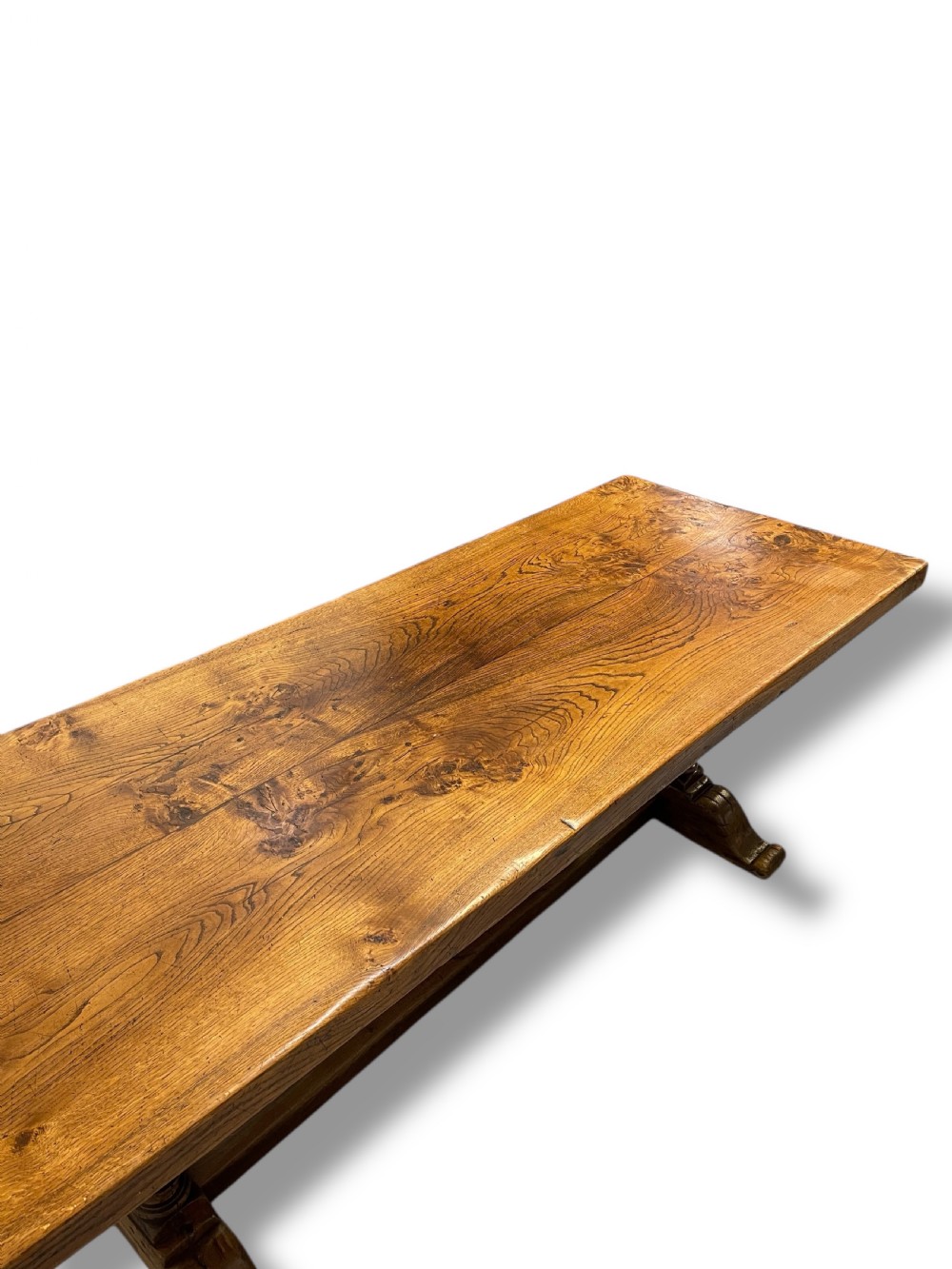 A solid warm brown oak refectory dining table featuring a thick rectangular top supported by double turned columns and a central stretcher. View XI