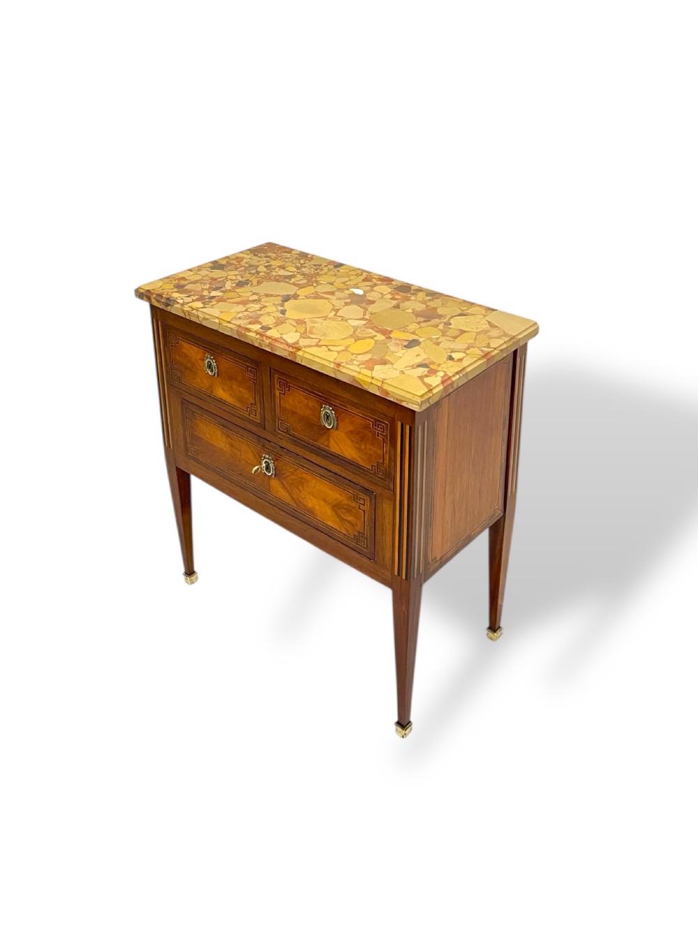 A Louis XVI style wooden commode featuring geometric parquetry inlay, a variegated marble top, three drawers with brass escutcheons, and tapered square legs. View II