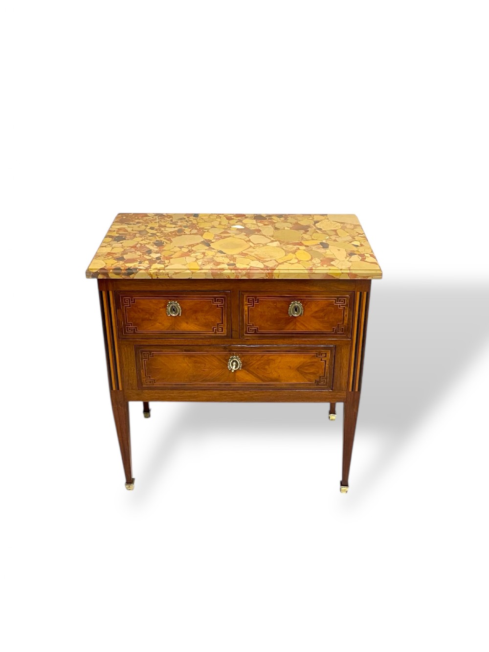 A Louis XVI style wooden commode featuring geometric parquetry inlay, a variegated marble top, three drawers with brass escutcheons, and tapered square legs. View III