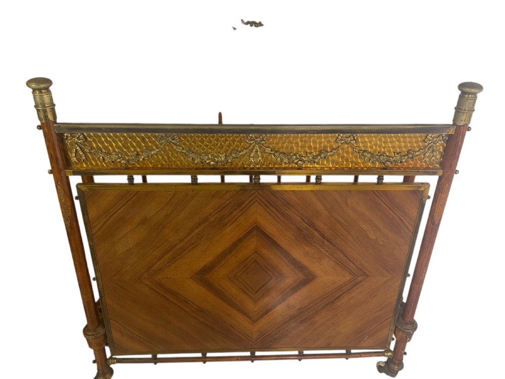 A pair of Edwardian brass and walnut single bed frames featuring diamond veneer panels and brass swag detailing. View VI