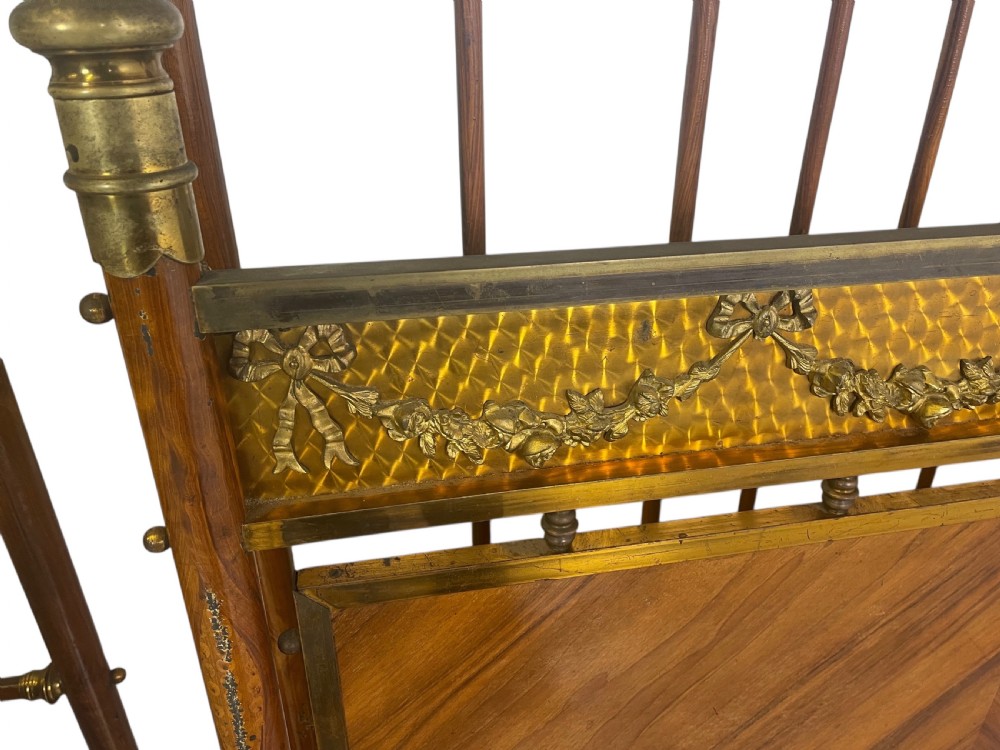 A pair of Edwardian brass and walnut single bed frames featuring diamond veneer panels and brass swag detailing. View VII