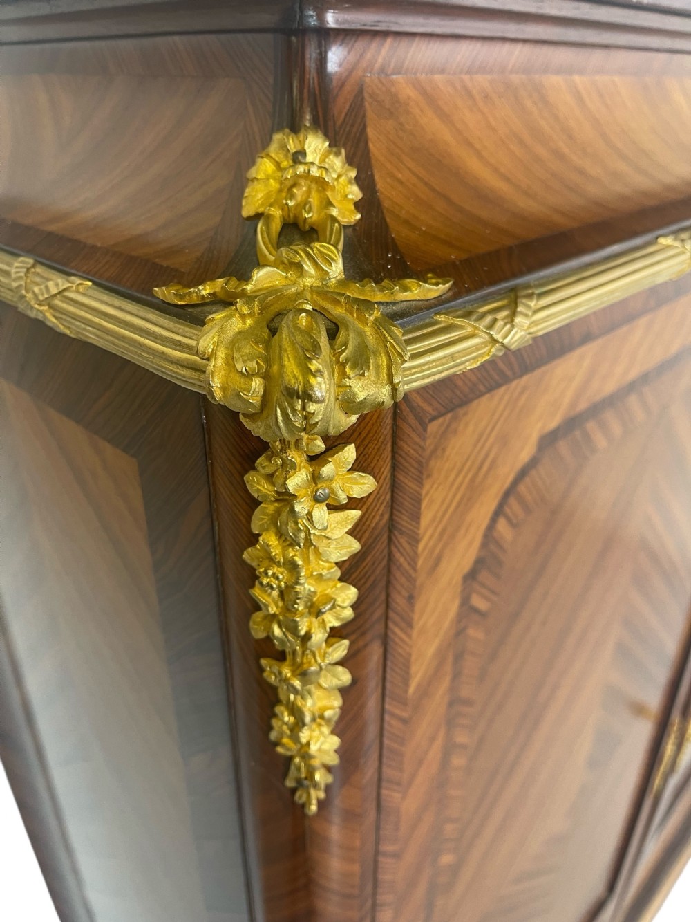 A French Louis XV style marquetry cabinet featuring geometric veneer panelling, gilt-bronze corner mounts, and a dark marble top. View III