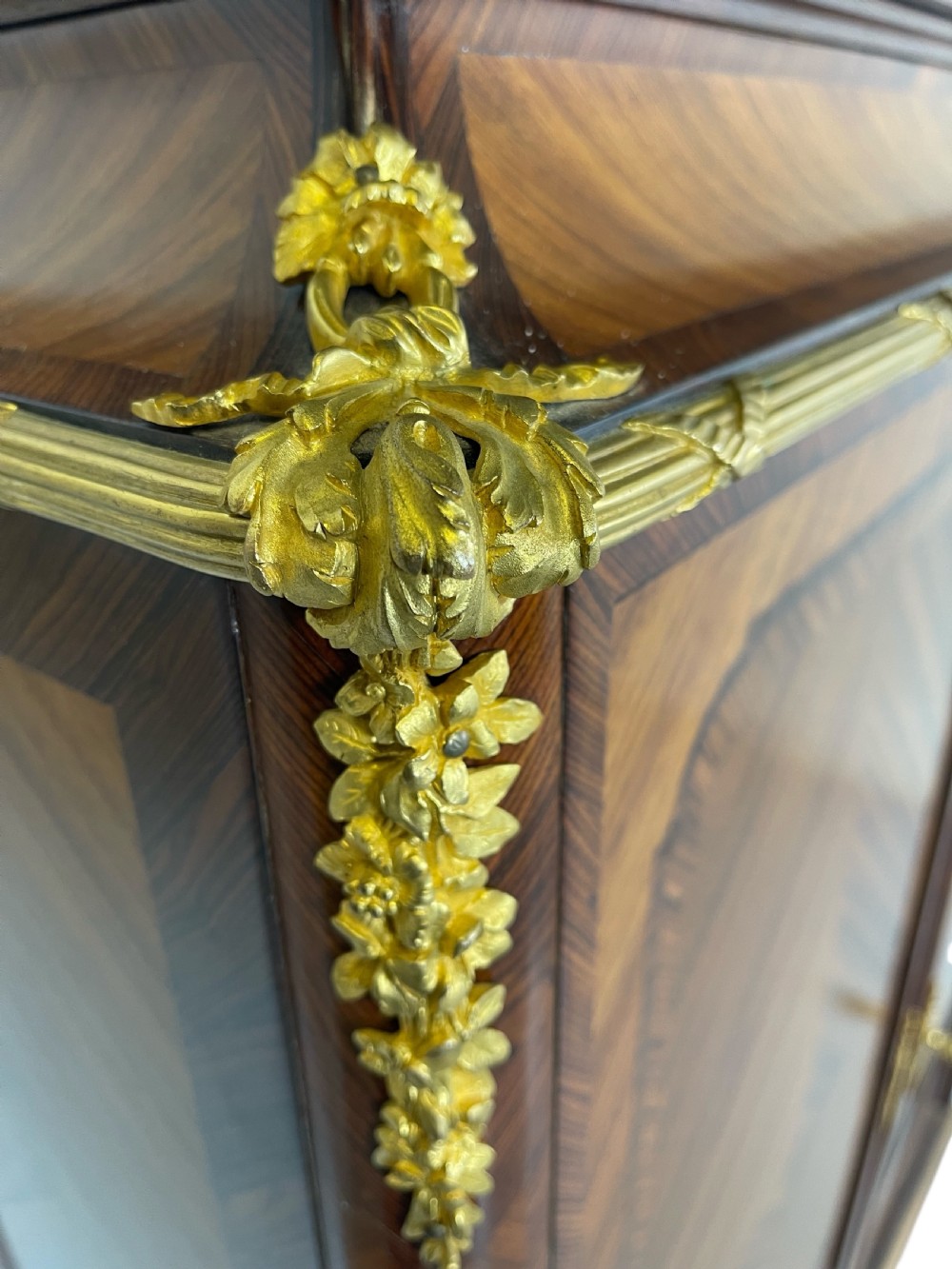 A French Louis XV style marquetry cabinet featuring geometric veneer panelling, gilt-bronze corner mounts, and a dark marble top. View IV