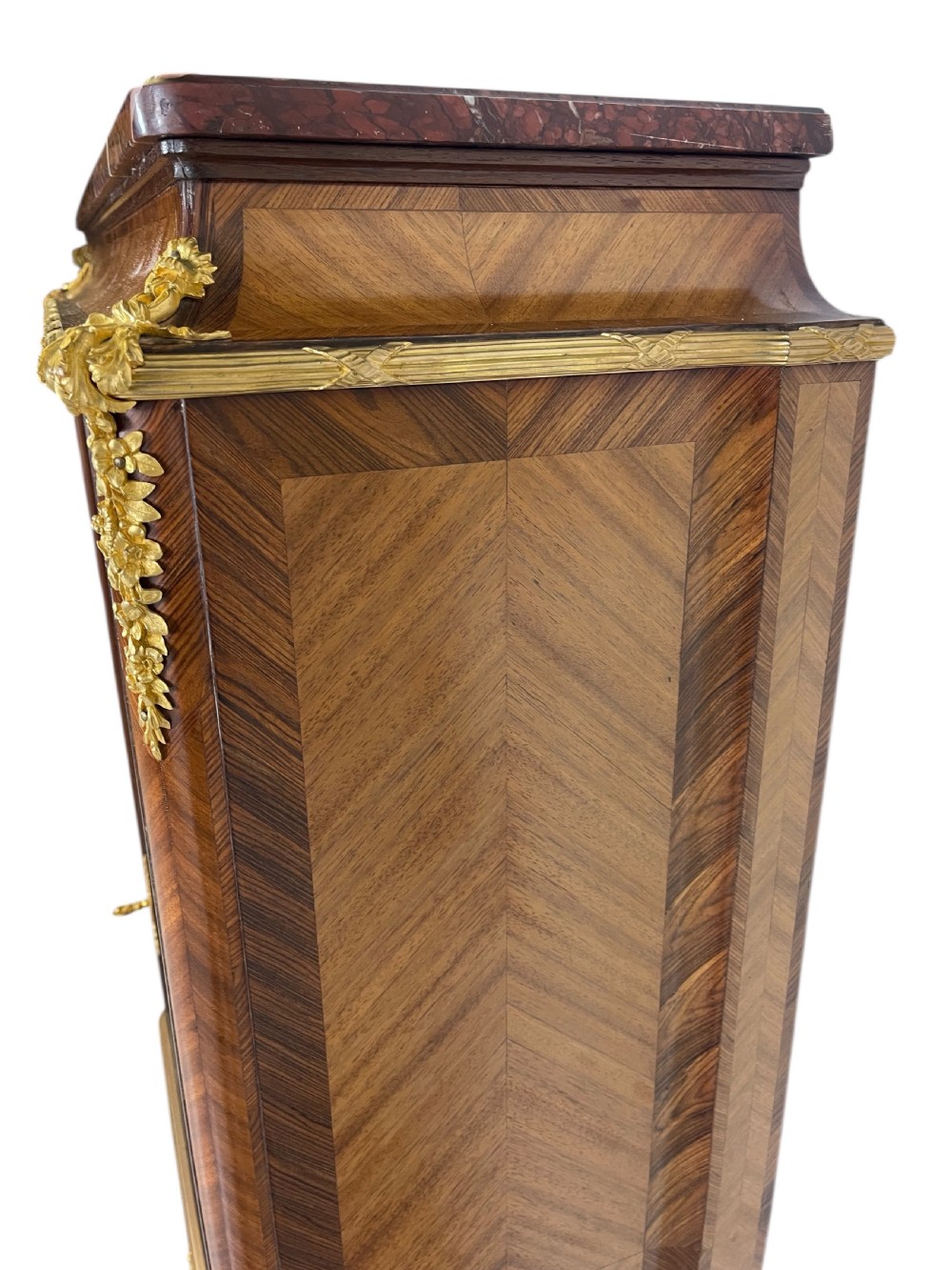 A French Louis XV style marquetry cabinet featuring geometric veneer panelling, gilt-bronze corner mounts, and a dark marble top. View XII