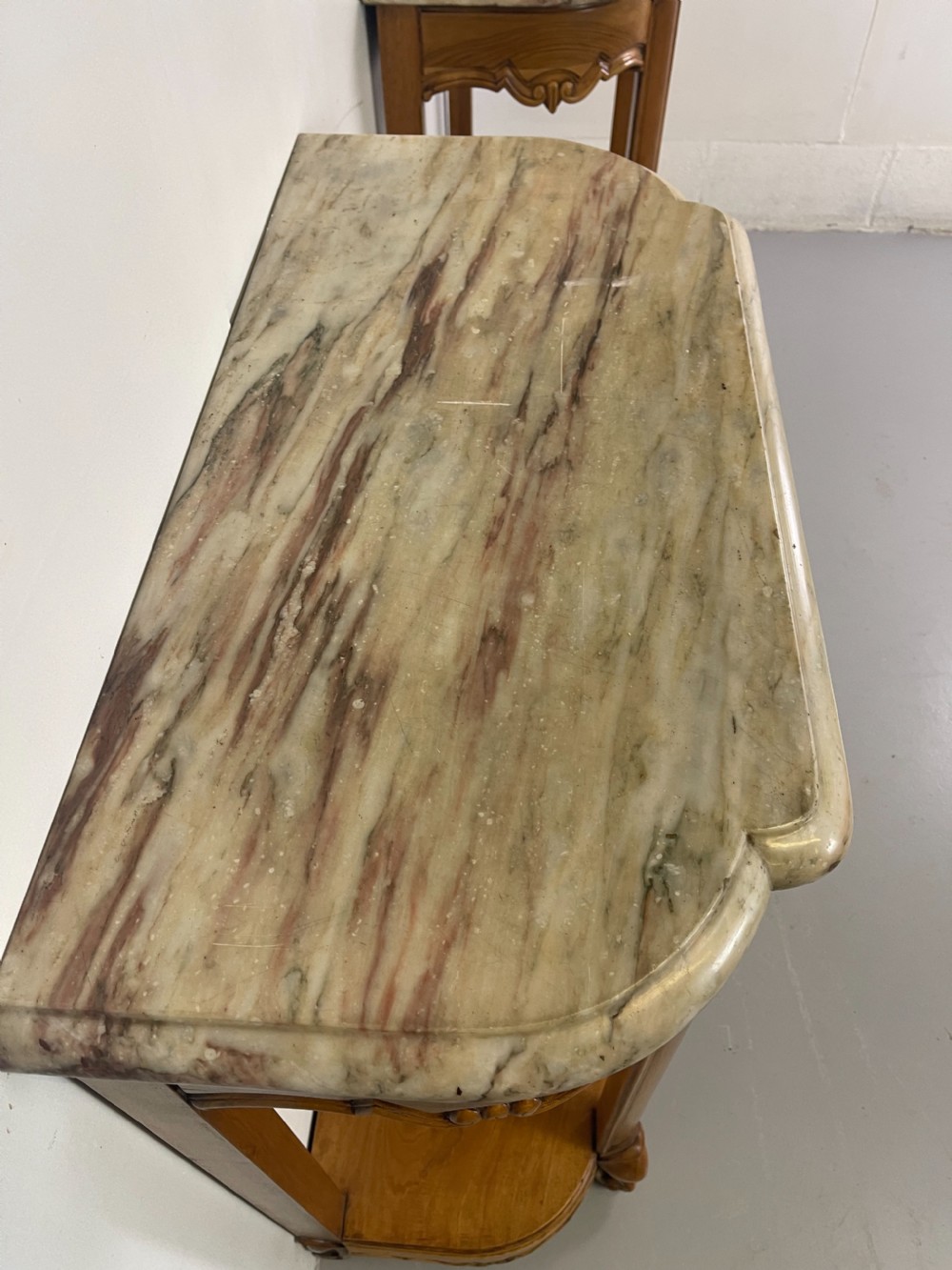 A pair of French Louis XV style walnut console tables featuring shaped marble tops, carved shell aprons, lower shelves, and cabriole legs. View III