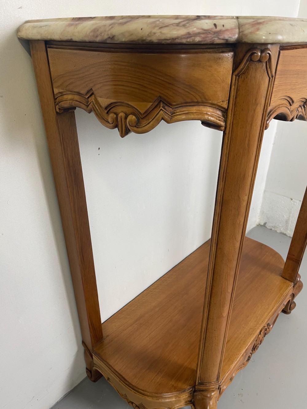 A pair of French Louis XV style walnut console tables featuring shaped marble tops, carved shell aprons, lower shelves, and cabriole legs. View VI
