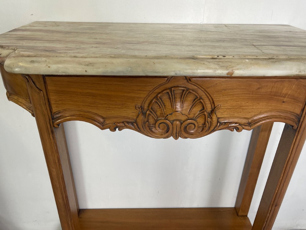 A pair of French Louis XV style walnut console tables featuring shaped marble tops, carved shell aprons, lower shelves, and cabriole legs. View VII